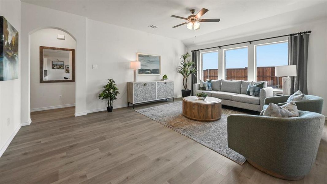 Living area with ceiling fan, wood finished floors, and arched walkways