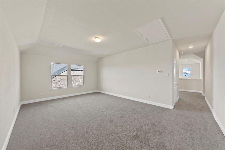 Unfurnished room featuring light colored carpet and lofted ceiling