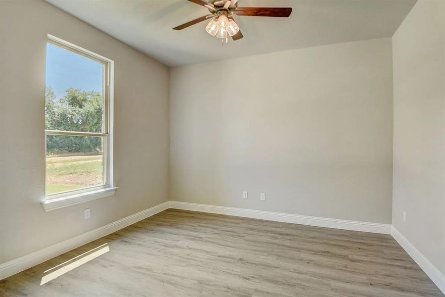 Unfurnished room featuring light wood-style floors, baseboards, and a ceiling fan