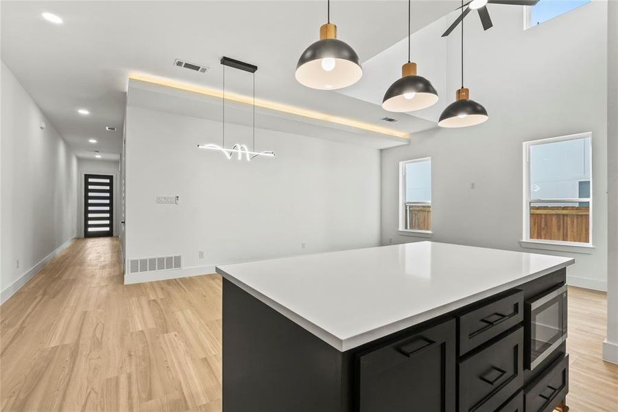 Kitchen with dark cabinetry, pendant lighting, a kitchen island, light countertops, and recessed lighting