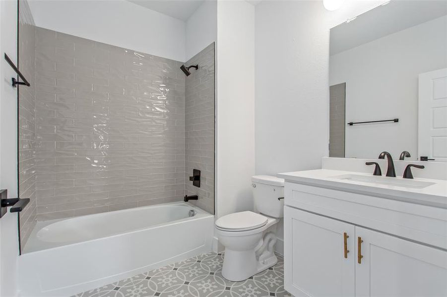 Full bathroom featuring tile patterned floors, vanity, tiled shower / bath combo, and toilet