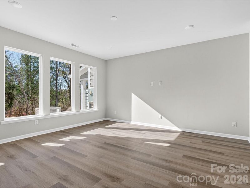 Light filled living room with picture windows allowing natural light to fill the space & views of the yard & woods