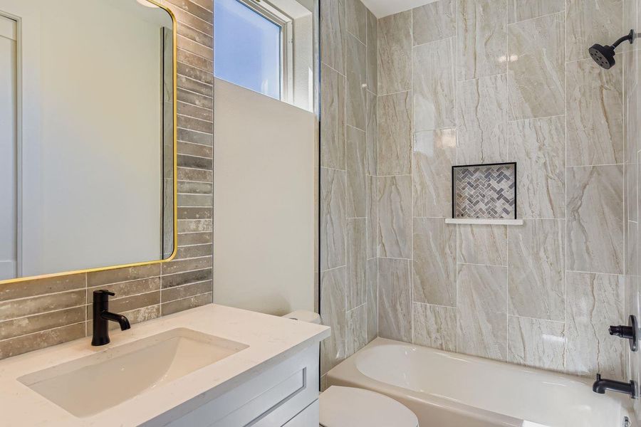 Full bath featuring bathtub / shower combination, vanity, and decorative backsplash Full bath featuring bathtub / shower combination, vanity, and decorative backsplash