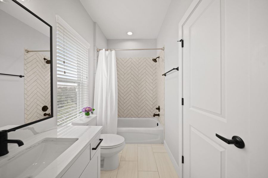 The stylish ensuite bath features ceramic tile floors, a quartz countertop with bold black fixtures and a combination tub/shower. The herringbone-patterned subway tile surround complements the design while a black-framed mirror and matching light fixture complete the modern aesthetic. Just beyond the entrance, a separate door leads to a generous closet, perfectly placed for everyday storage and convenience. The stylish ensuite bath features ceramic tile floors, a quartz countertop with bold black fixtures and a combination tub/shower. The herringbone-patterned subway tile surround complements the design while a black-framed mirror and matching light fixture complete the modern aesthetic. Just beyond the entrance, a separate door leads to a generous closet, perfectly placed for everyday storage and convenience.