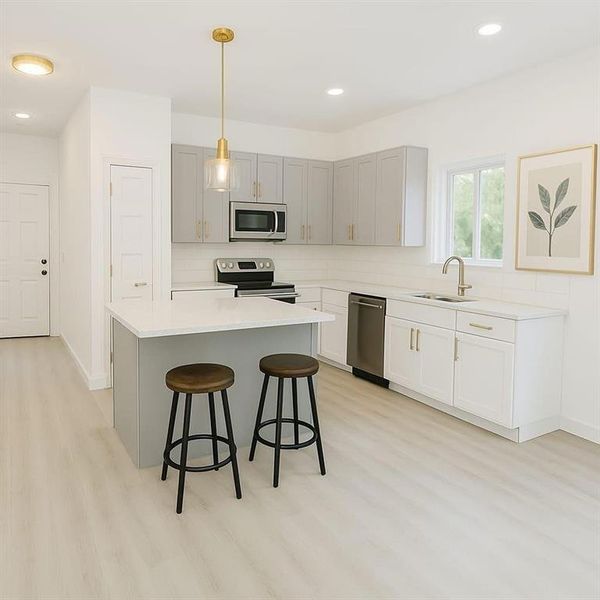 Kitchen with gray cabinets, hanging light fixtures, a kitchen island, stainless steel appliances, and a breakfast bar area Kitchen with gray cabinets, hanging light fixtures, a kitchen island, stainless steel appliances, and a breakfast bar area