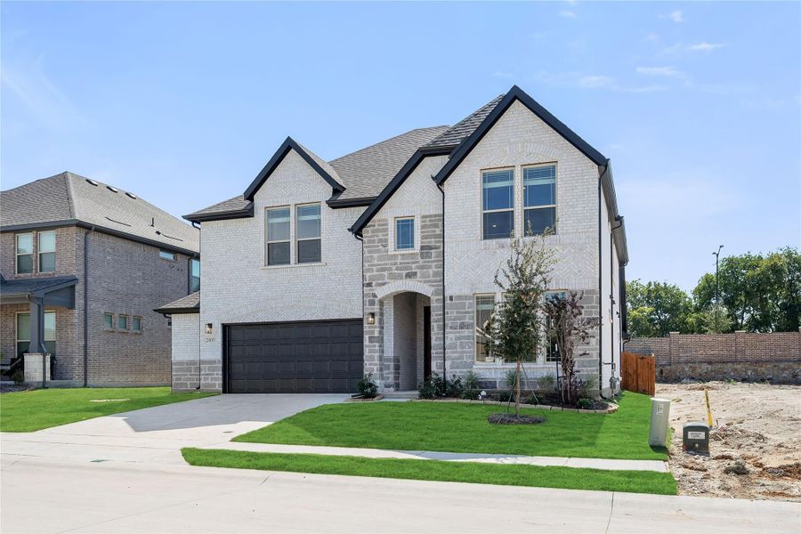 Two-story home with white brick and stone exterior, two-car garage, and arched entryway