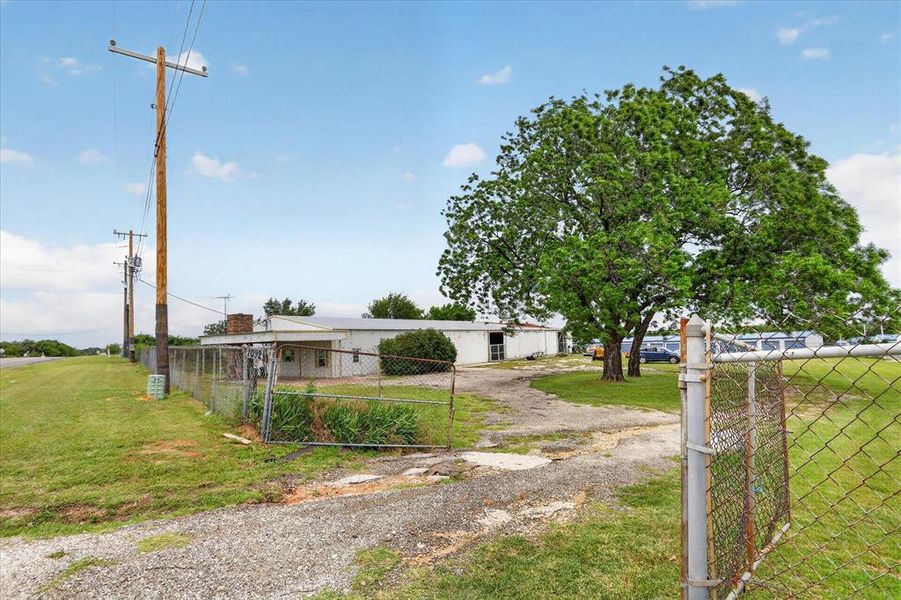 Chain-link fencing with gate encompasses the property, featuring a gravel driveway