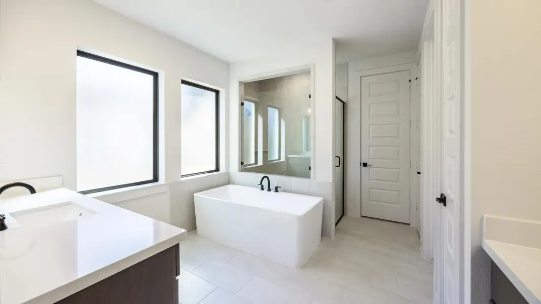 Bathroom featuring vanity, a freestanding tub, a shower stall, and light tile patterned floors Bathroom featuring vanity, a freestanding tub, a shower stall, and light tile patterned floors