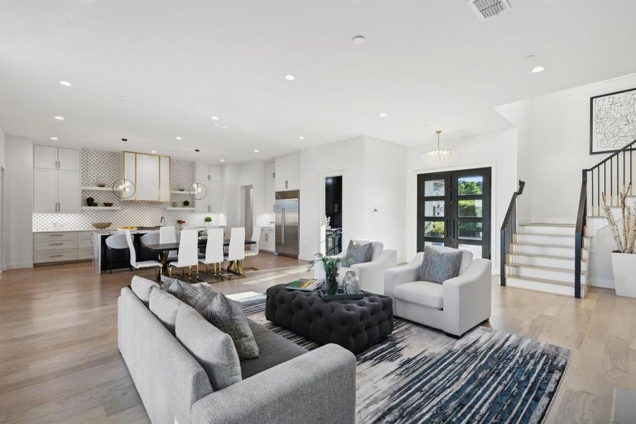 Kitchen featuring white cabinets, tasteful backsplash, light wood-type flooring, and a center island with sink