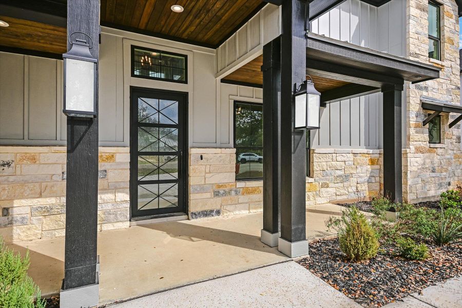 Entrance to property with stone siding, board and batten siding, and covered porch