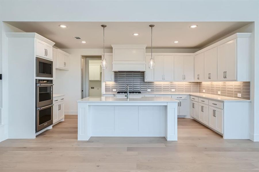 Kitchen with light hardwood / wood-style flooring, decorative light fixtures, and white cabinets