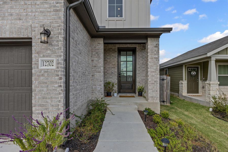 Property entrance with brick siding, board and batten siding, and a front yard