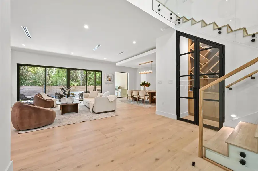 Living room with light wood finished floors, recessed lighting, a chandelier, and stairway