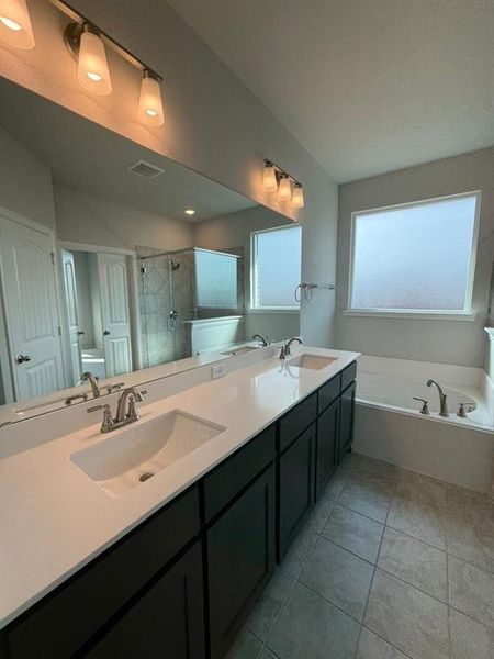 Full bathroom featuring a garden tub, double vanity, a shower stall, and light tile patterned floors Full bathroom featuring a garden tub, double vanity, a shower stall, and light tile patterned floors