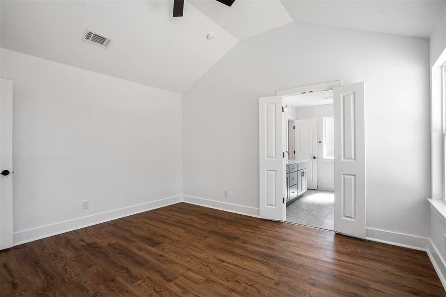 Unfurnished bedroom featuring wood finished floors, visible vents, baseboards, ceiling fan, and vaulted ceiling