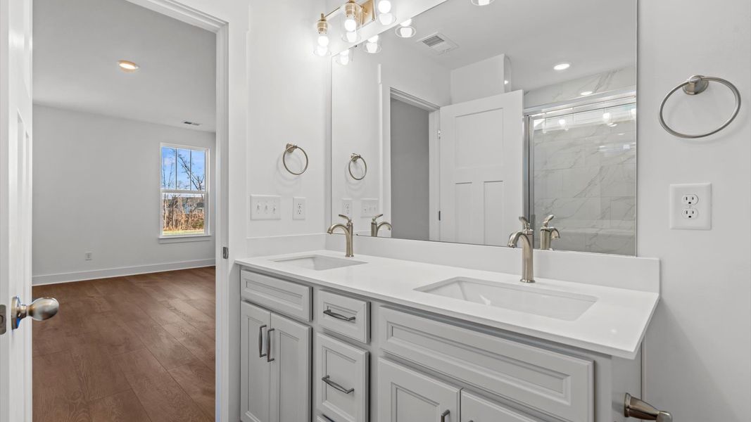 Highly functional and elegant en-suite with dual vanities, tiled walk-in shower, and refined finishes