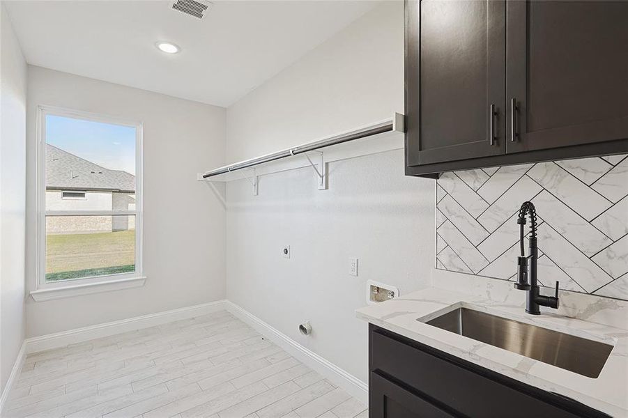 Washroom with sink, cabinets, washer hookup, electric dryer hookup, and light wood-type flooring