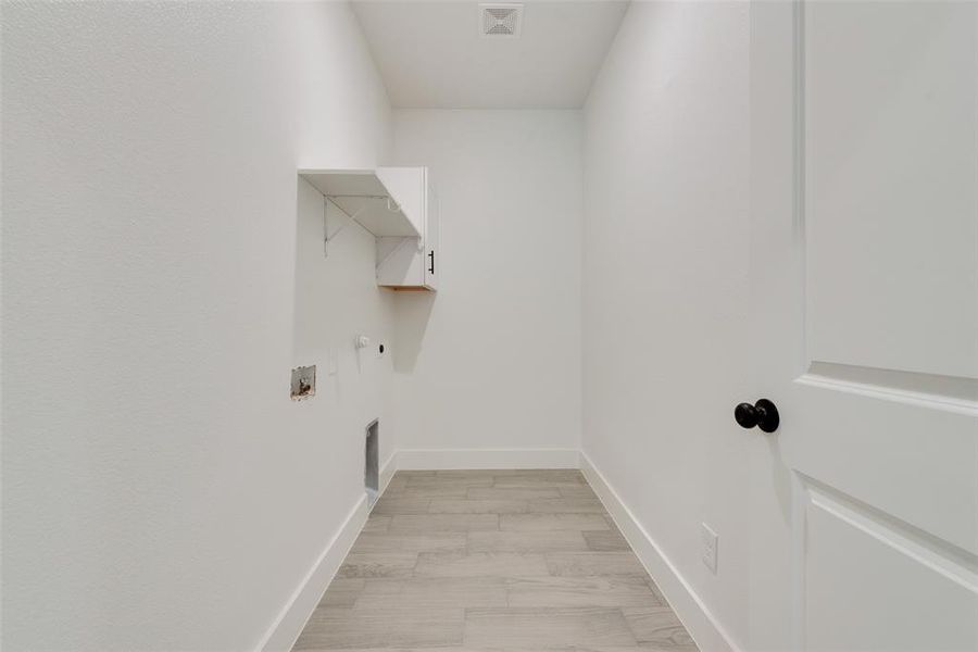 Clothes washing area featuring hookup for a washing machine, visible vents, electric dryer hookup, laundry area, and baseboards