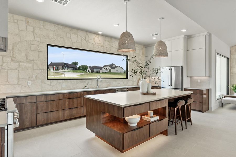 Kitchen with modern cabinets, appliances with stainless steel finishes, pendant lighting, a kitchen breakfast bar, and a kitchen island