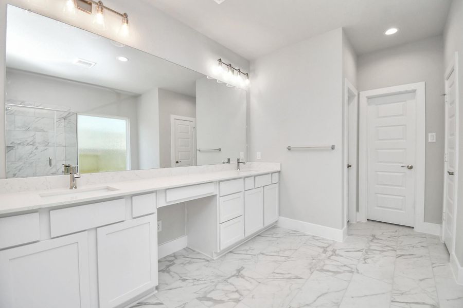 Escape to a spa-like oasis in this primary bathroom. Enjoy a walk-in shower with tile surround, a separate garden tub with custom detailing, and an elegant vanity featuring light countertops, modern hardware, and beautiful recessed lights. Experience luxury and relaxation in every detail. Sample photo of completed home with similar floor plan. Actual colors and selections may vary.