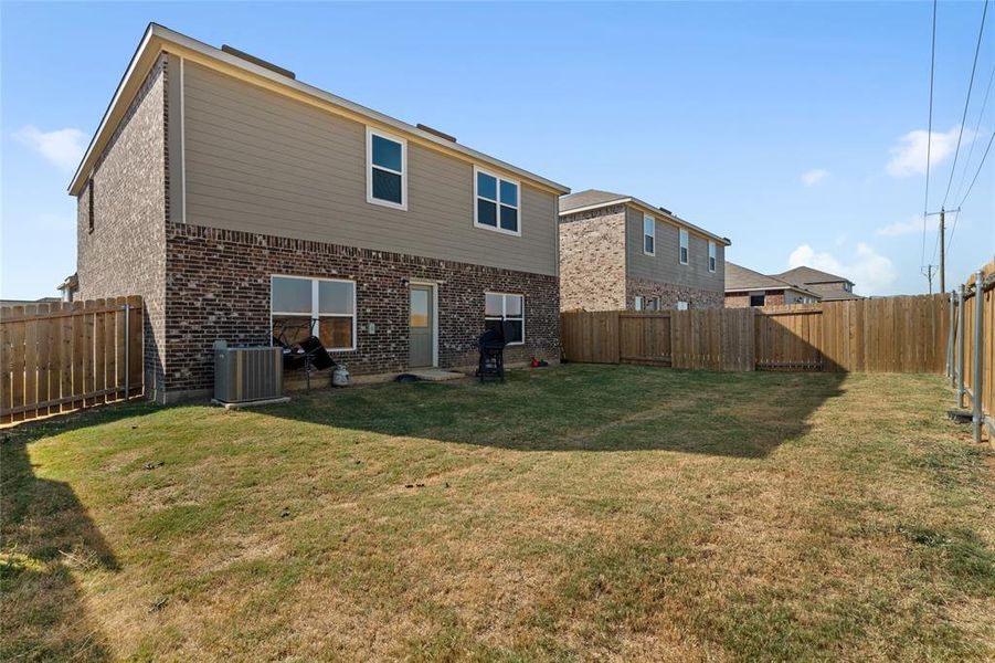 Rear view of house with a fenced backyard and brick siding