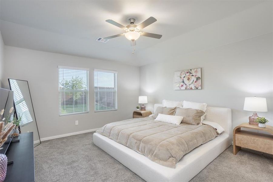 Carpeted bedroom featuring multiple windows and ceiling fan Carpeted bedroom featuring multiple windows and ceiling fan