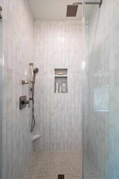 Custom glass and tile walk in shower with a rain spout and a shower arm