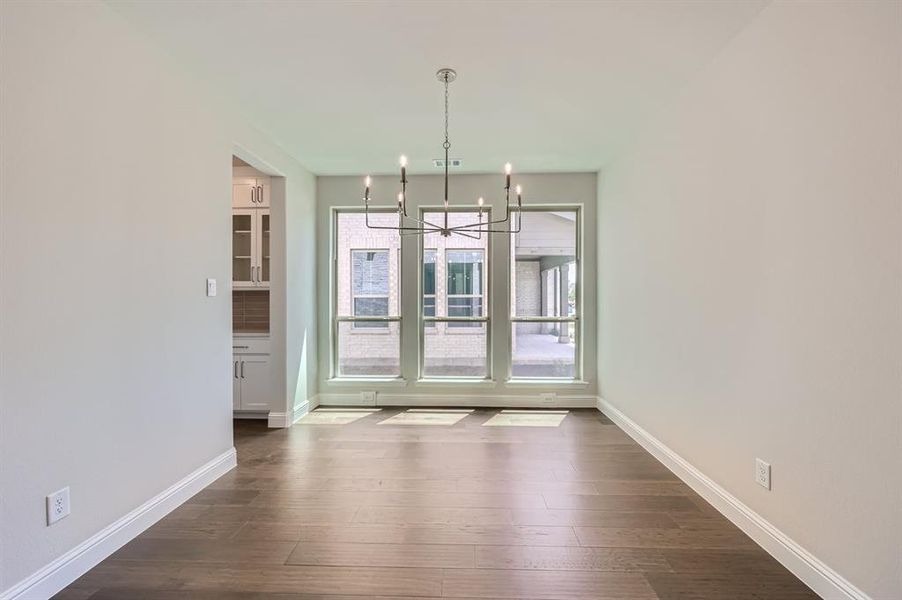 Unfurnished dining area with a notable chandelier and dark wood-type flooring