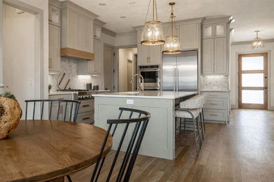 Kitchen featuring tasteful backsplash, gray cabinets, stainless steel built in fridge, and light wood-style floors