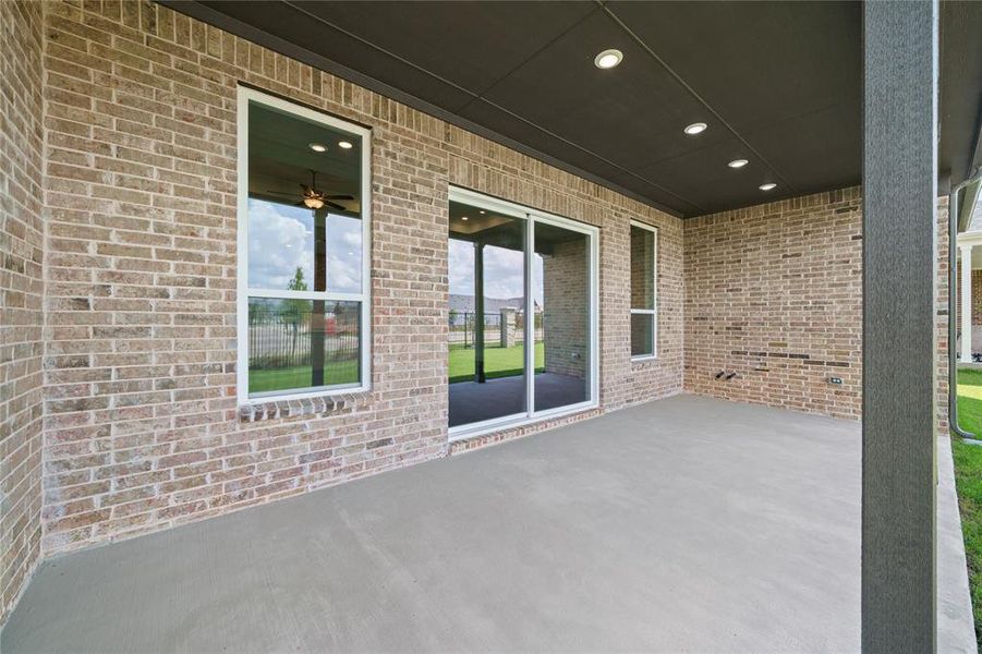 Covered concrete patio featuring recessed lighting, brick exterior, and a sliding glass door