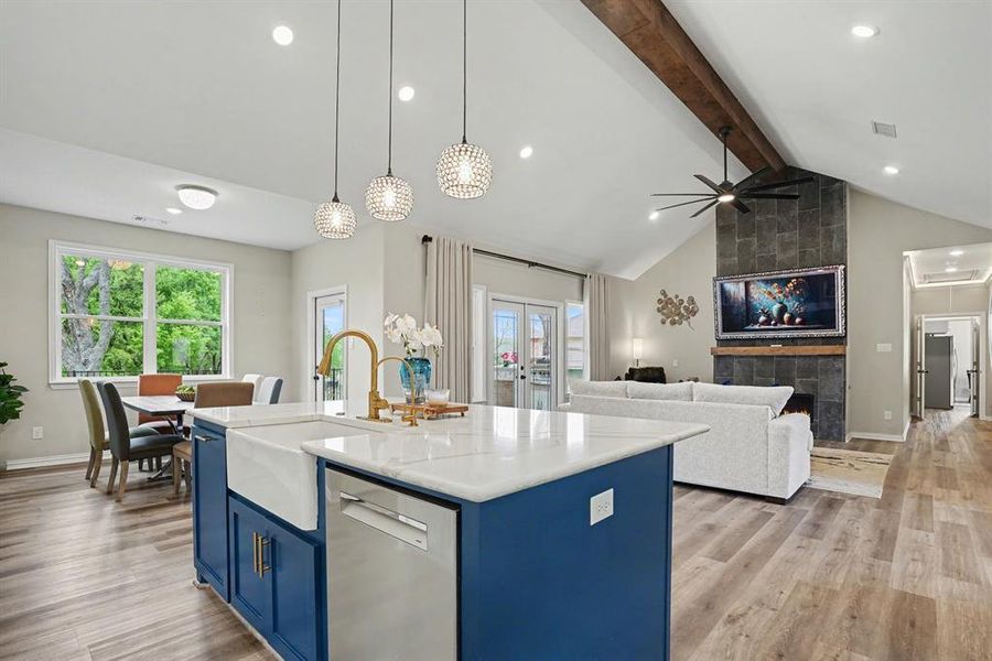 Kitchen featuring blue cabinets, stainless steel appliances, open floor plan, light wood-type flooring, and an island with sink