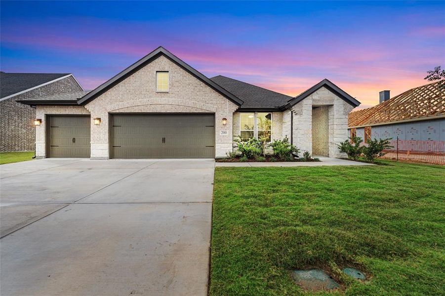 View of front of home with concrete driveway, a yard, a garage, roof with shingles, and brick siding View of front of home with concrete driveway, a yard, a garage, roof with shingles, and brick siding