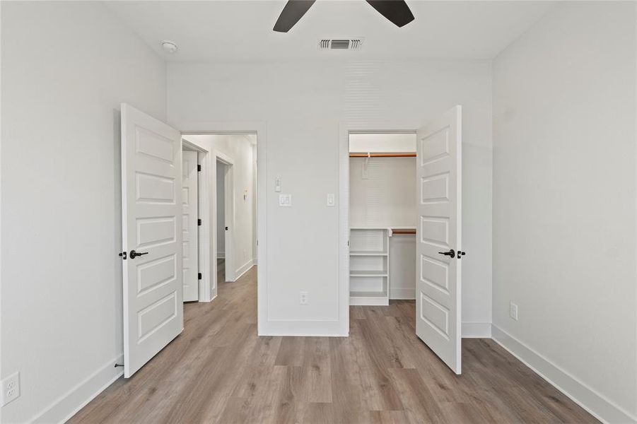 Unfurnished bedroom featuring baseboards, a walk in closet, visible vents, and light wood-style floors