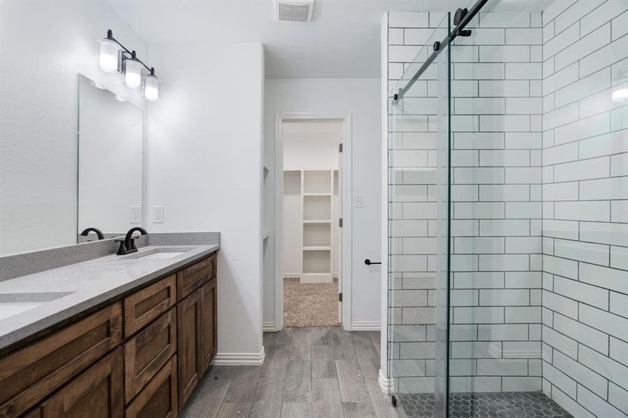 Bathroom with a shower stall, light wood-style floors, double vanity, and a walk in closet Bathroom with a shower stall, light wood-style floors, double vanity, and a walk in closet