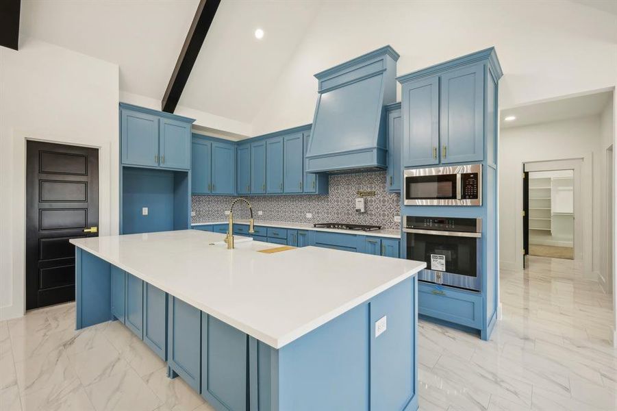 Kitchen featuring sink, an island with sink, custom exhaust hood, and appliances with stainless steel finishes