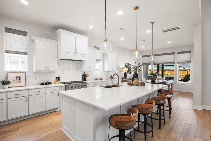 The chef-inspired kitchen features a gas cooktop, three ovens, abundant workspace, and an open-concept design, making it perfect for preparing meals and entertaining with ease.