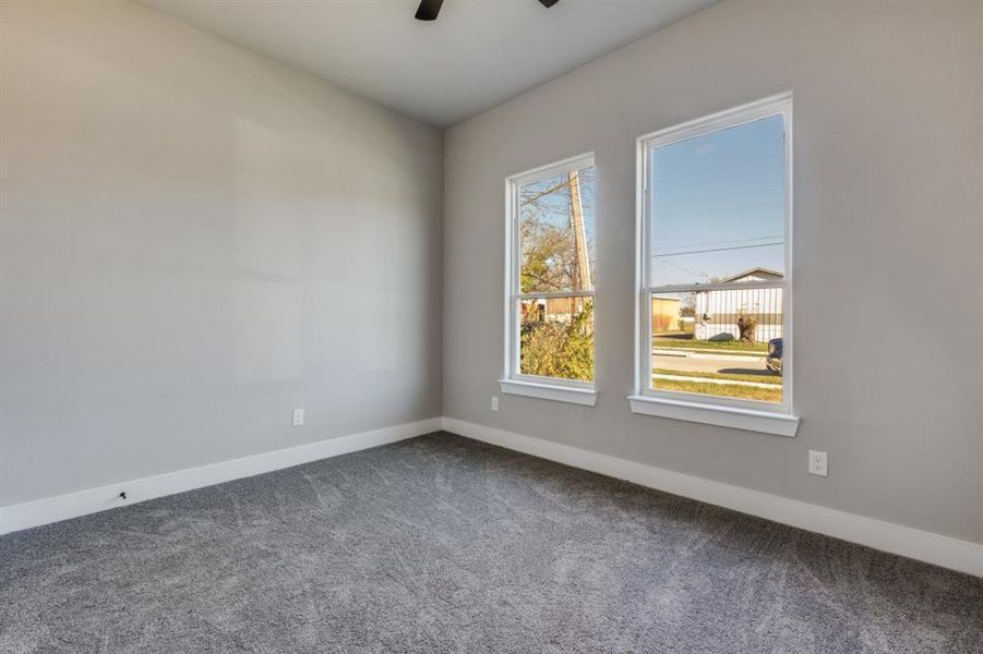 Carpeted spare room with baseboards and ceiling fan