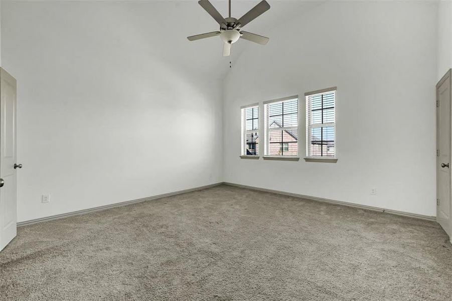 Spare room featuring high vaulted ceiling, light carpet, and ceiling fan Spare room featuring high vaulted ceiling, light carpet, and ceiling fan