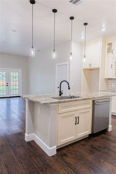 Kitchen with light stone counters, decorative light fixtures, dishwasher, and dark wood finished floors Kitchen with light stone counters, decorative light fixtures, dishwasher, and dark wood finished floors