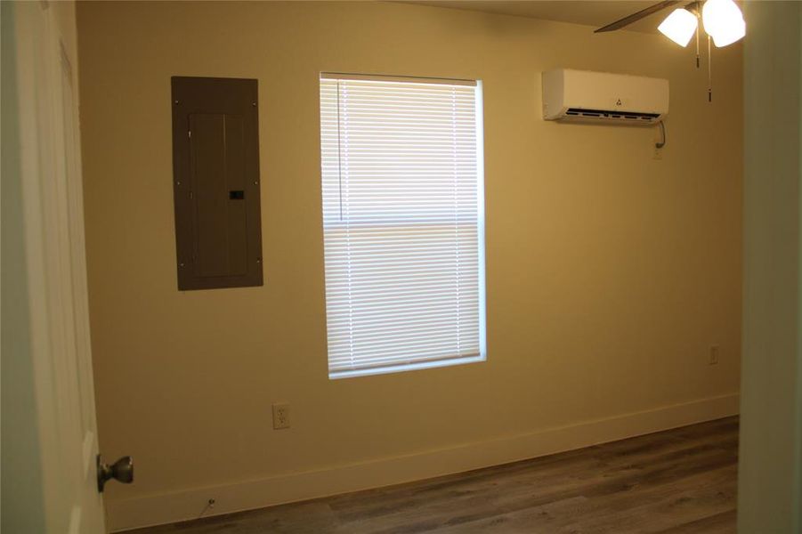 Spare room featuring electric panel, dark wood finished floors, ceiling fan, and a wall mounted air conditioner