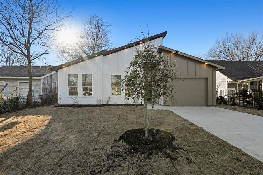 View of front of house with a garage, driveway, fence, and board and batten siding