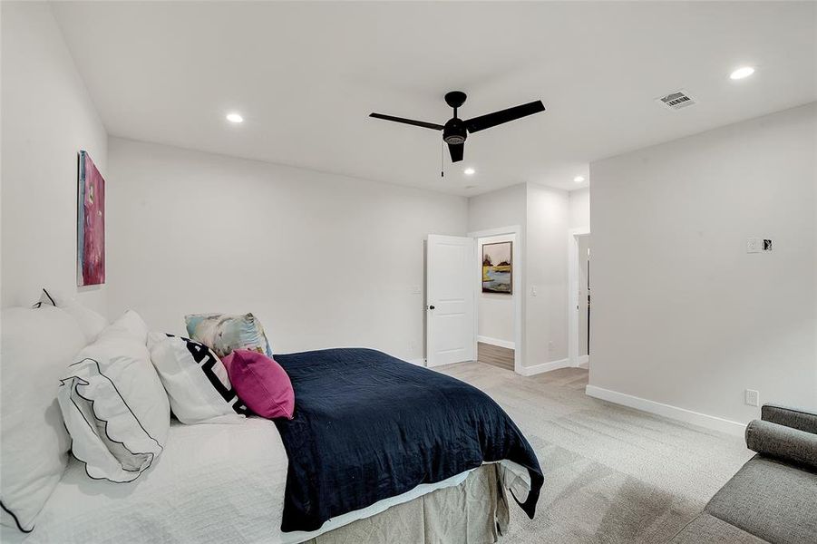 Primary Bedroom with ceiling fan and light colored carpet