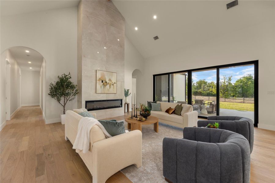 Living area featuring light wood-style flooring, vaulted ceiling, arched walkways, recessed lighting, and a fireplace