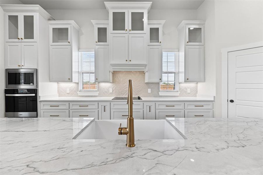 Kitchen featuring white cabinetry, tasteful backsplash, stainless steel appliances, light stone counters, and plenty of natural light Kitchen featuring white cabinetry, tasteful backsplash, stainless steel appliances, light stone counters, and plenty of natural light