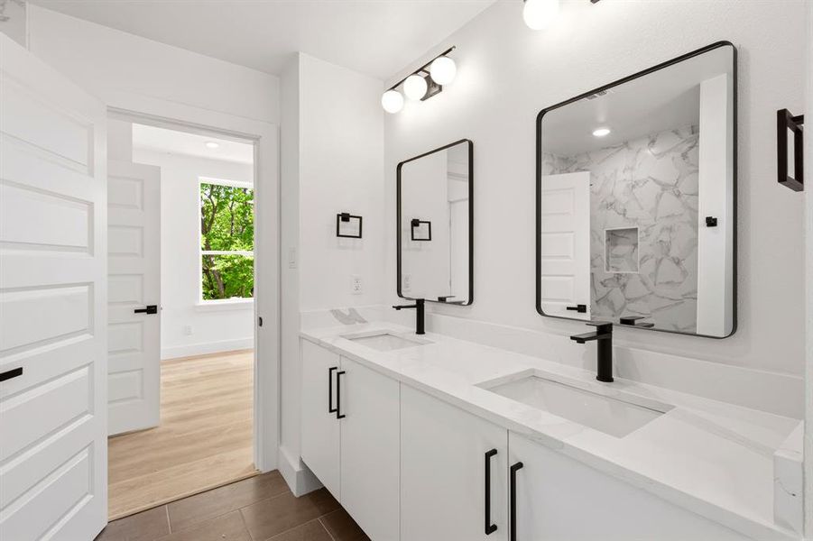 Bathroom featuring a double vanity with white cabinets, white countertops, dual rectangular sinks, and matte black hardware