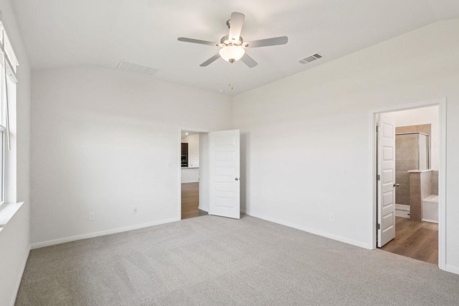 Unfurnished bedroom with carpet, lofted ceiling, a ceiling fan, and connected bathroom Unfurnished bedroom with carpet, lofted ceiling, a ceiling fan, and connected bathroom