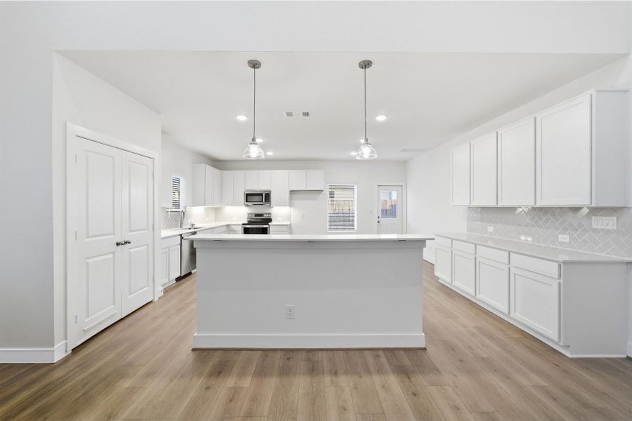Kitchen featuring white cabinets, a center island, stainless steel appliances, backsplash, and hanging light fixtures