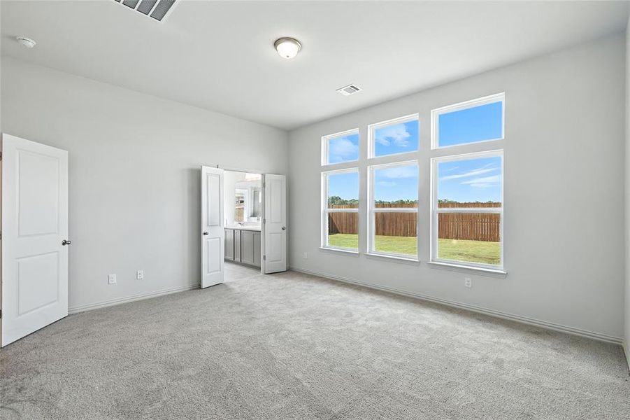 Unfurnished bedroom featuring light carpet and ensuite bath Unfurnished bedroom featuring light carpet and ensuite bath
