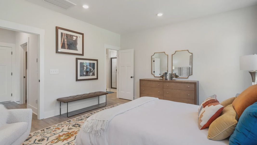 Elegant primary suite with hardwood flooring and superior natural light in this accomplished DRB Homes design