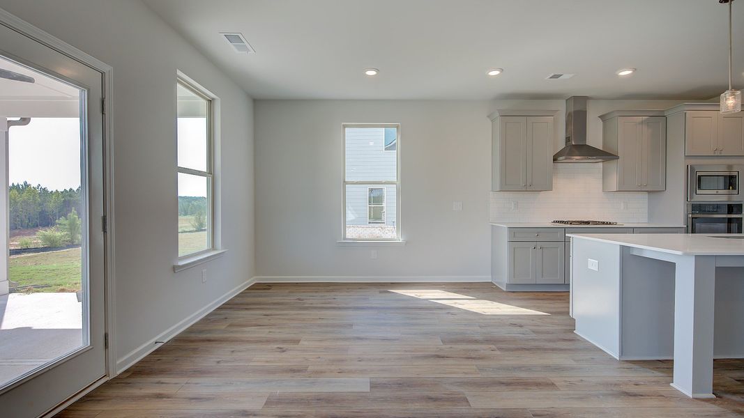 McKinley II open breakfast area with LVP flooring and view of backyard at Brighton in Locust Grove, GA.